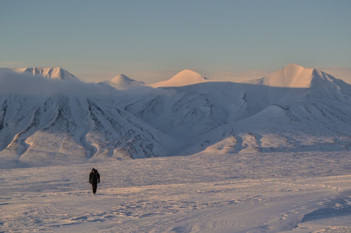 Walking to a survey area near Longyearbyen. The wide flat terrain was one of the Svalbard sites, chosen to represent the low-gradient snow terrain typical of Arctic catchments.