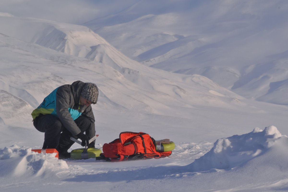 Setting a ground control point before a flight near Longyearbyen. GCPs are physical targets placed on the snow surface to anchor the SfM point cloud to real-world coordinates.